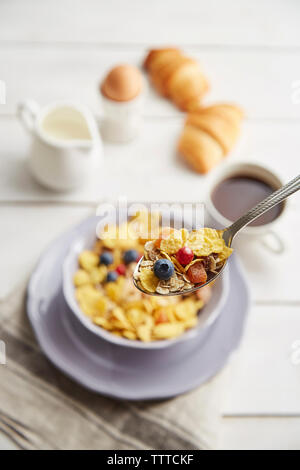 Close-up of breakfast cereals in spoon over wooden table Stock Photo