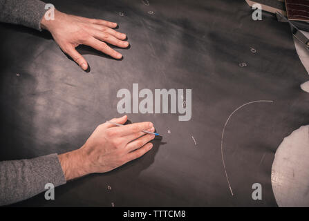 cropped hands of shoemaker measuring leather on workbench at workshop Stock Photo
