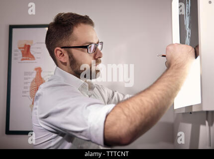 Side view of male doctor examining medical x-ray at hospital Stock Photo