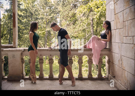 Young woman looking at friends practicing ballet in old building Stock Photo