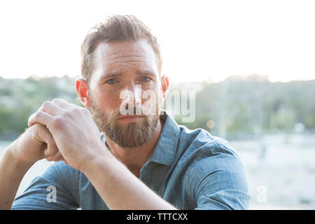 Close-up portrait of serious man sitting against sky Stock Photo