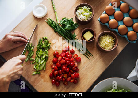 Overhead view of woman chopping asparagus in kitchen Stock Photo