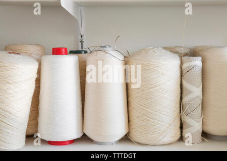 Close-up of white spools on shelf at home studio Stock Photo