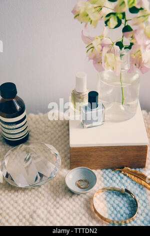 Beauty products with jewelry and crystal by flower vase on table