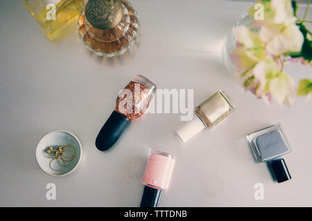 High angle view of beauty products with jewelry by flower vase on table