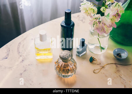 High angle view of beauty products with jewelry by flower vase on table