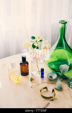 High angle view of beauty products and jewelry by flower vase on table