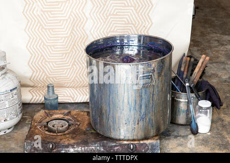 Metal container on old rusty stove at workshop Stock Photo