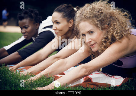Determined athletes exercising on field at park Stock Photo