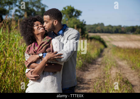 Happy couple romancing at farm on sunny day Stock Photo