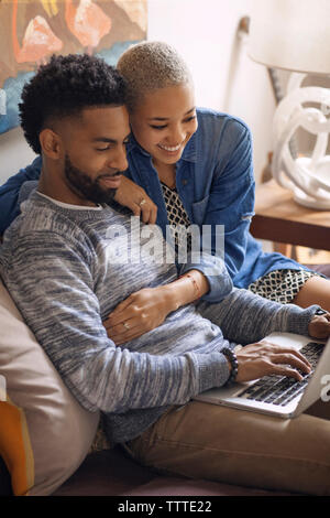 Couple using laptop computer while sitting on bed at home Stock Photo
