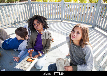 High angle view of students relaxing in gazebo during field trip Stock Photo