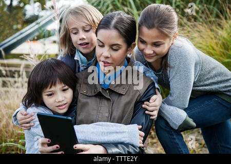 Teacher showing tablet computer to school children during field trip Stock Photo