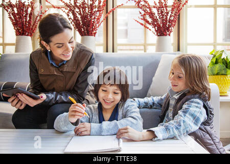 Teacher looking at students writing in room during field trip Stock Photo
