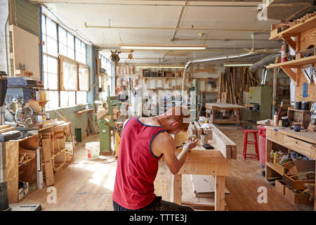 Rear view of carpenter working in workshop Stock Photo
