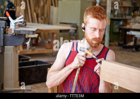 Carpenter wearing earphones while working in workshop Stock Photo