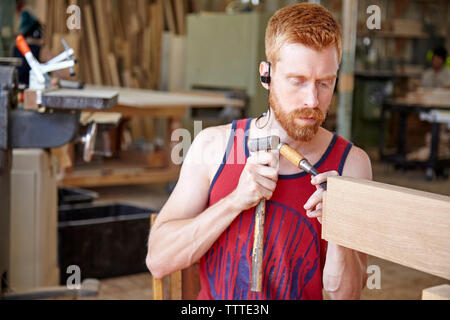 Craftsperson wearing earphones while working in workshop Stock Photo