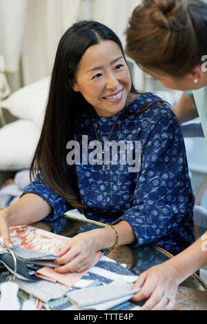 High angle view of happy interior designers discussing over textiles in workshop Stock Photo