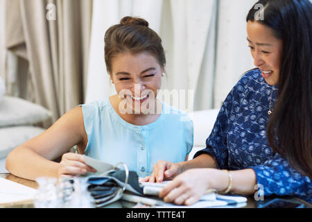 Happy interior designers discussing over textiles while sitting in workshop Stock Photo