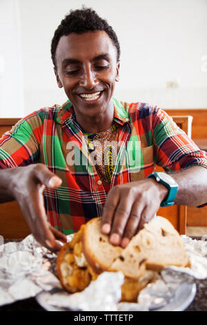 BERMUDA. St. George. Chef Marcus Samuelsson about to eat a fish sandwich at Art Mel's Spicy Dicy Restaurant in St. George. Stock Photo