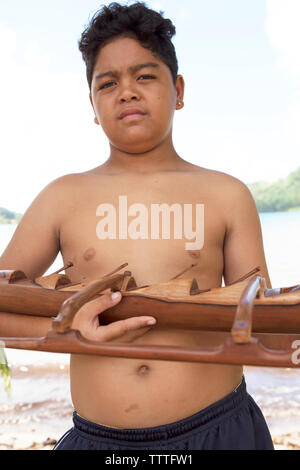 FRENCH POLYNESIA, Tahaa Island. Chris, a young boy holding a wooden canoe made by his father. His father is a sculpture and sells his pieces from thei Stock Photo