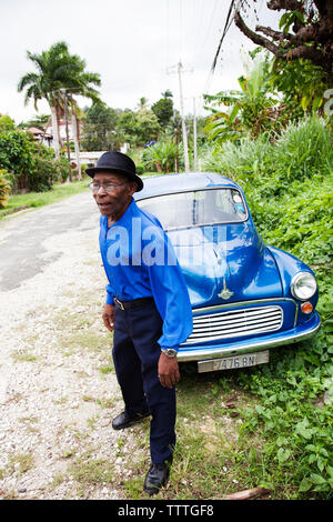 JAMAICA, Port Antonio. Joseph 'Powder' Bennett of the Mento band, The Jolly Boys standing in front of a vintage blue car. Stock Photo