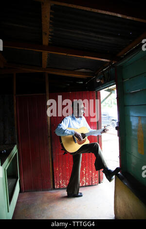 JAMAICA, Port Antonio. Albert Minott of the Mento band, The Jolly Boys playing guitar at the Willow Wind Bar. Stock Photo