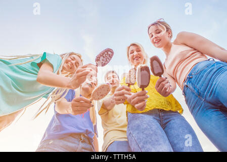 Group of young friends enjoying ice cream in the summer, view from below Stock Photo