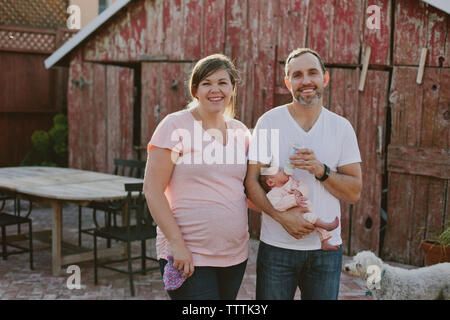 Portrait of smiling woman and man with baby girl and dog in yard Stock Photo