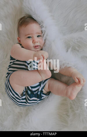 Overhead portrait of cute baby boy lying on rug Stock Photo