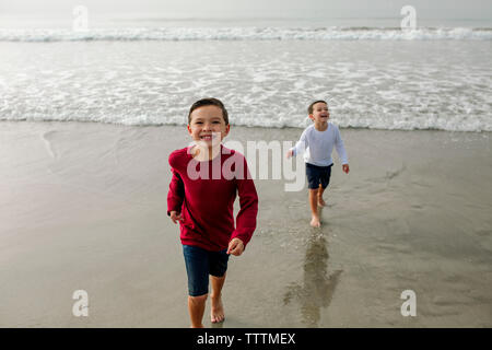 Portrait of cheerful boy with brother standing in background on shore Stock Photo