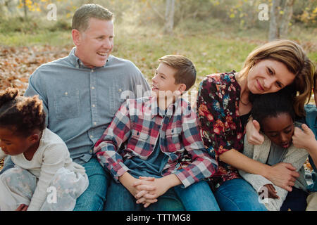 Happy family sitting on field at park Stock Photo