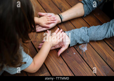 Cropped image of mother and daughter playing on wooden table at backyard Stock Photo