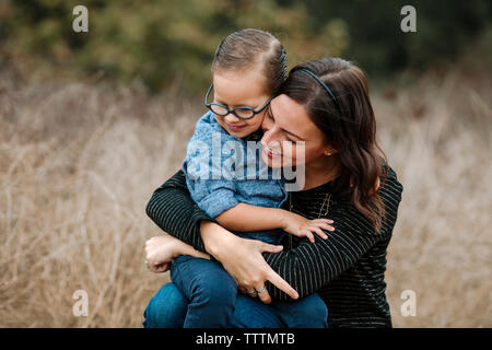 Happy mother embracing son while sitting on grassy field Stock Photo