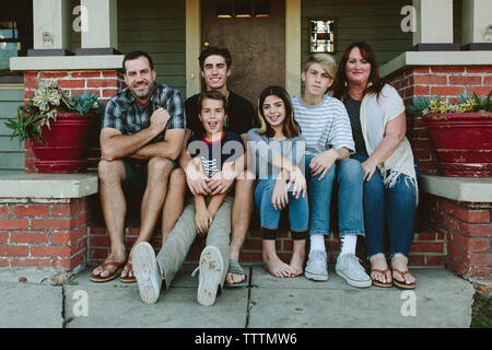 Portrait of smiling family sitting on steps by house Stock Photo