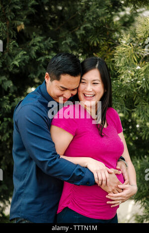 Loving man embracing pregnant woman at park Stock Photo