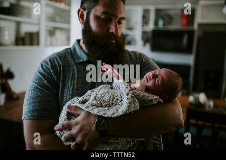 Bearded father carrying cute sleeping daughter while standing at home Stock Photo