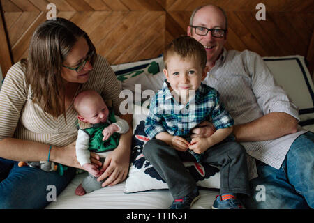 Happy family with newborn baby boy resting on bed at home Stock Photo