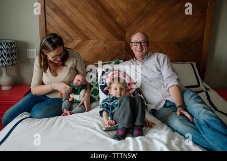 Family with newborn baby boy resting on bed at home Stock Photo