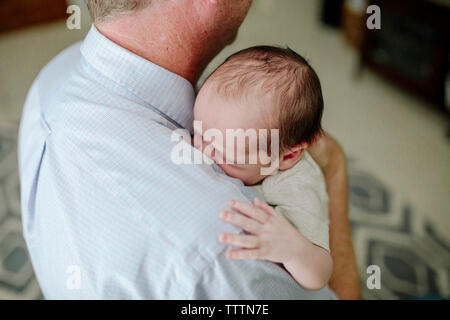 High angle view of father carrying cute newborn son at home Stock Photo