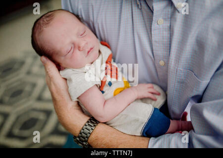 Midsection of father carrying cute newborn sleeping son at home Stock Photo