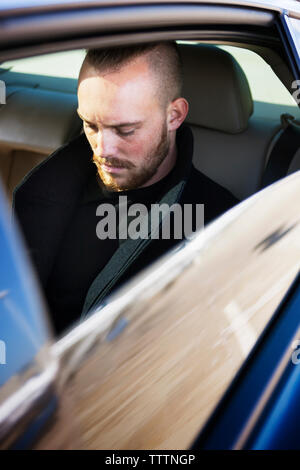 Young man looking down while travelling in car Stock Photo