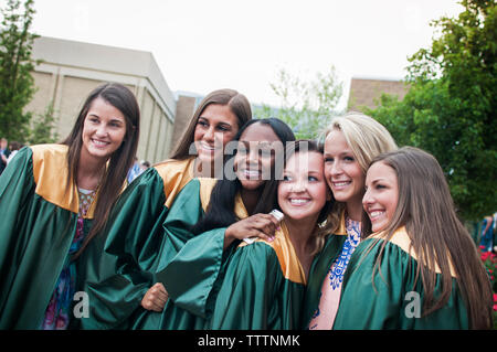 Happy graduate friends posing for photograph at campus Stock Photo