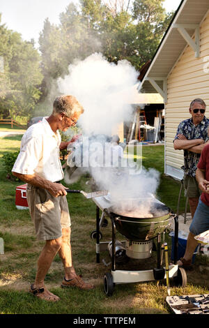 Friends cooking food in barbecue grill in backyard Stock Photo
