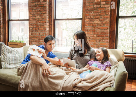 Girl showing tablet computer to parents while sitting on sofa at home Stock Photo