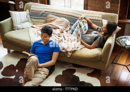 Couple reading book and magazine while relaxing at home Stock Photo