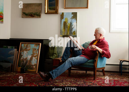 Man looking at painting while sitting on armchair Stock Photo