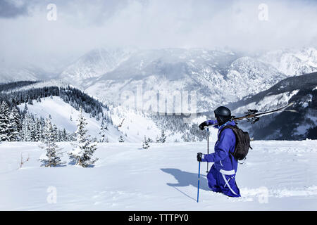 Skier walking on snow covered mountain against sky Stock Photo