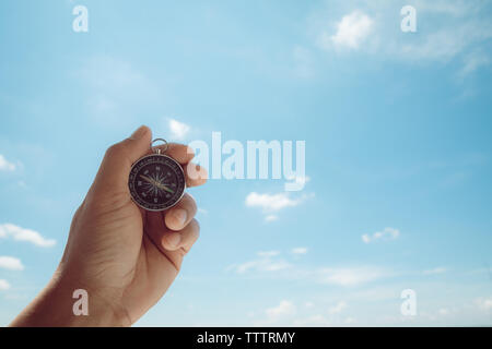 Male hands holding a compass on the sky background Stock Photo