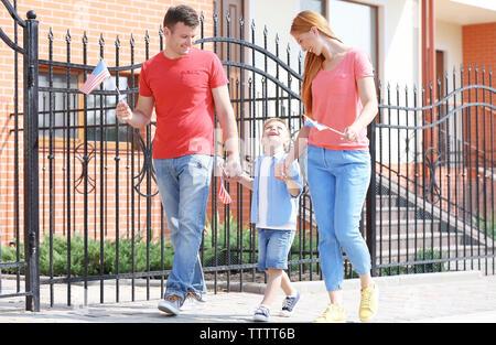 Happy family with little American flags walking on pavement Stock Photo